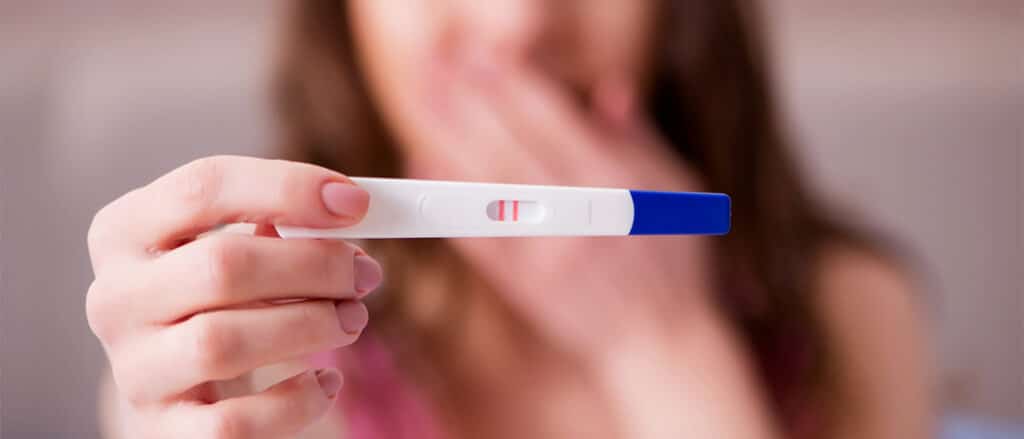 Een vrouw die een positieve zwangerschapstest toont.